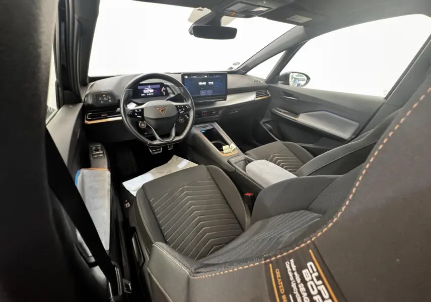 Vue intérieure avant droite du CUPRA BORN gris foncé, avec volant cuir multifonctions et écran tactile central.