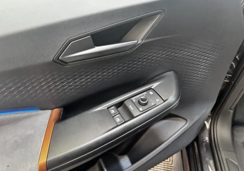 Vue rapprochée de la porte avant gauche gris foncé du CUPRA BORN avec commandes de vitres et poignée intégrée.