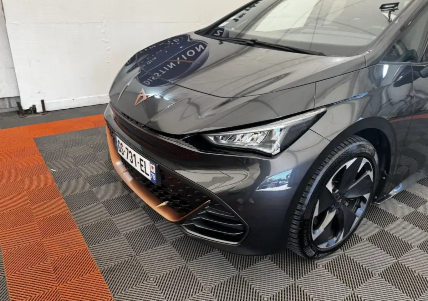 Vue 3/4 avant droit d'une CUPRA BORN gris foncé avec détails cuivrés et jantes noires distinctives.