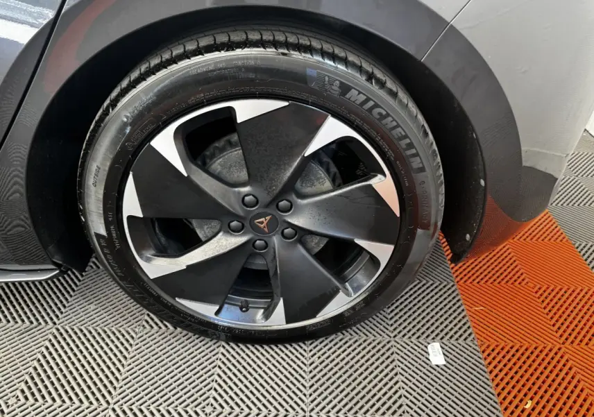 Gros plan sur la roue avant droite du CUPRA BORN gris foncé, jante noire et argent avec logo CUPRA central.