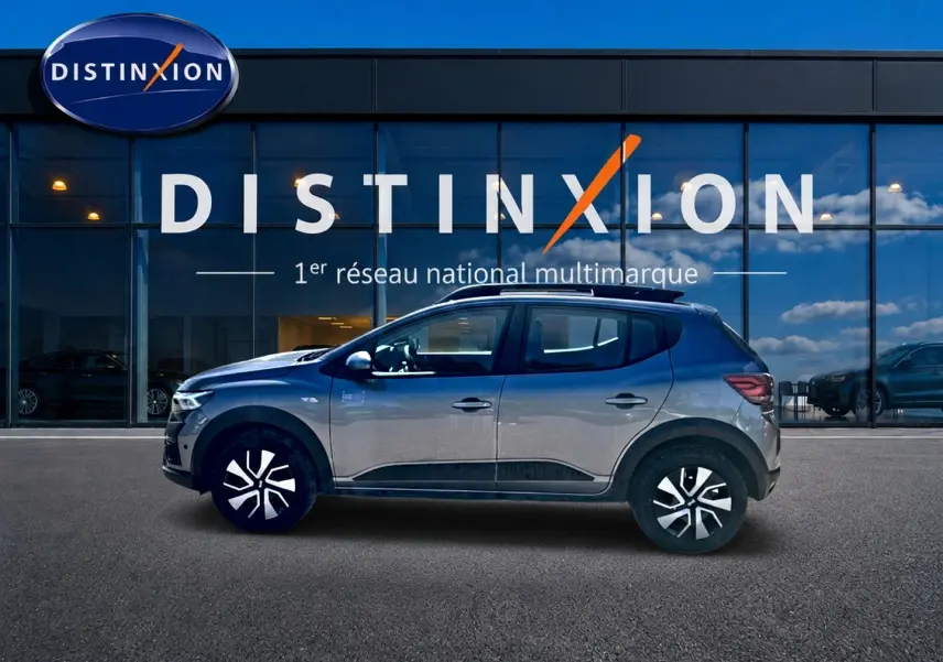 Profil droit de la Dacia Sandero Stepway gris schiste 2025 avec barres de toit et enjoliveurs noirs et argentés.