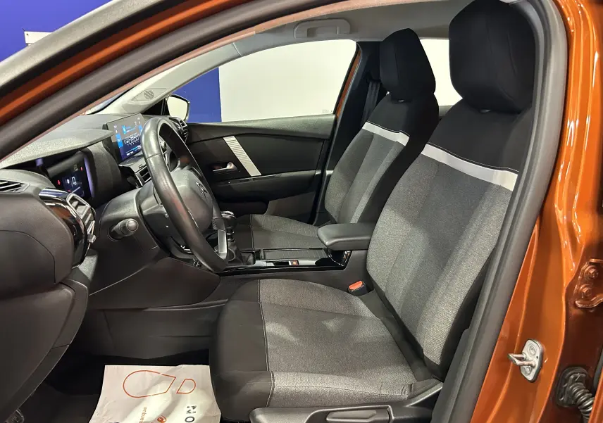 Vue intérieure côté conducteur de la CITROEN C4 PureTech 100 Feel orange 2021, sièges tissu gris et noir, tableau de bord moderne.