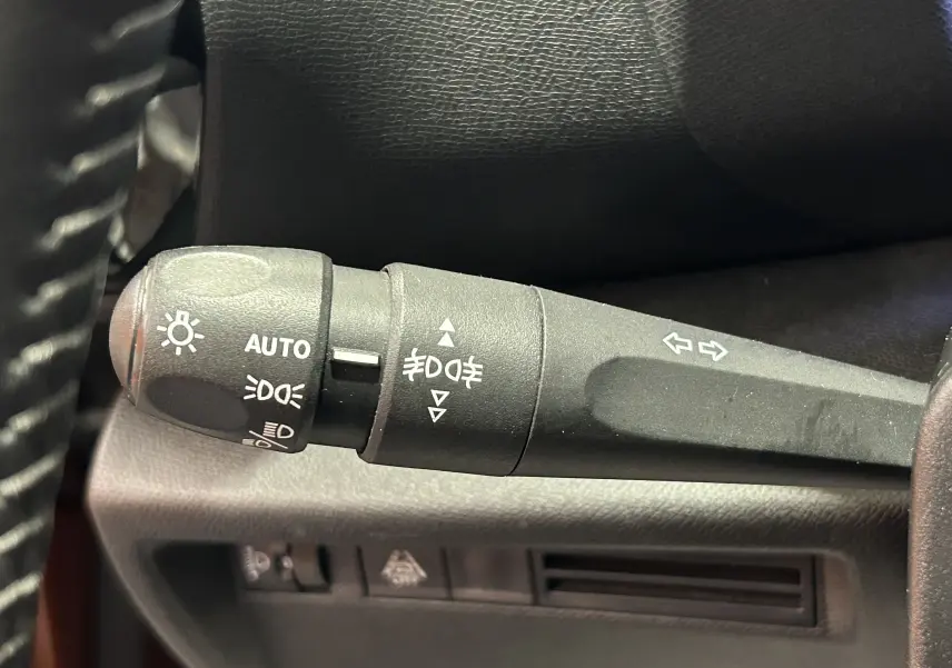 Gros plan sur le commodo gauche du tableau de bord de la Citroën C4 orange 2021, avec commandes des phares et clignotants.