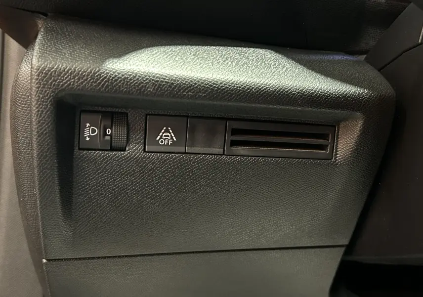 Détail du tableau de bord noir de la Citroën C4 PureTech 100 Feel 2021 avec commande de réglage des phares et désactivation de l'aide au maintien de voie.