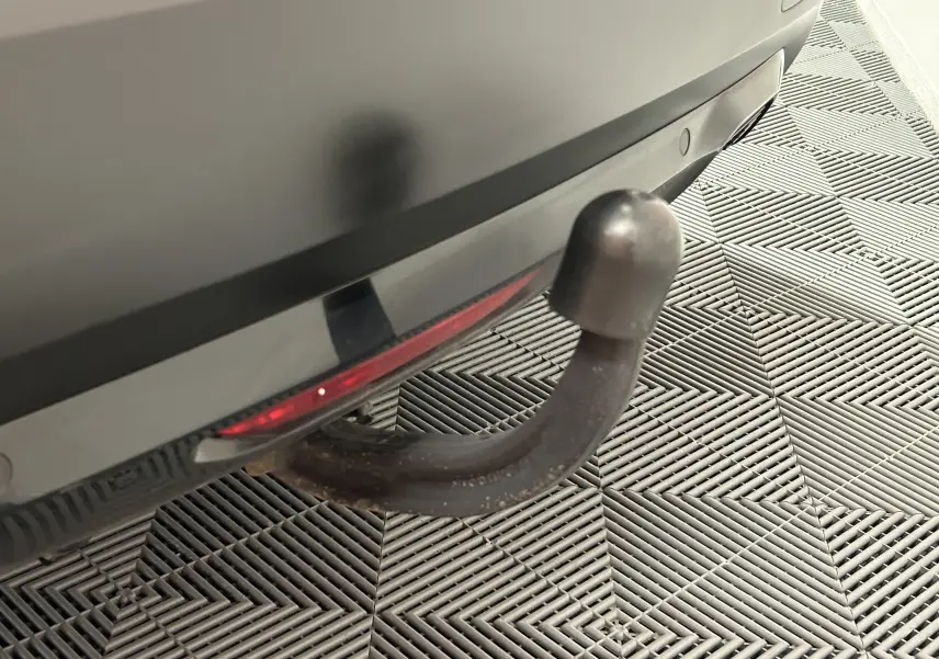 Gros plan sur l'attelage arrière noir du Citroën C4 orange PureTech 100 Feel de 2021, avec caméra de recul visible.