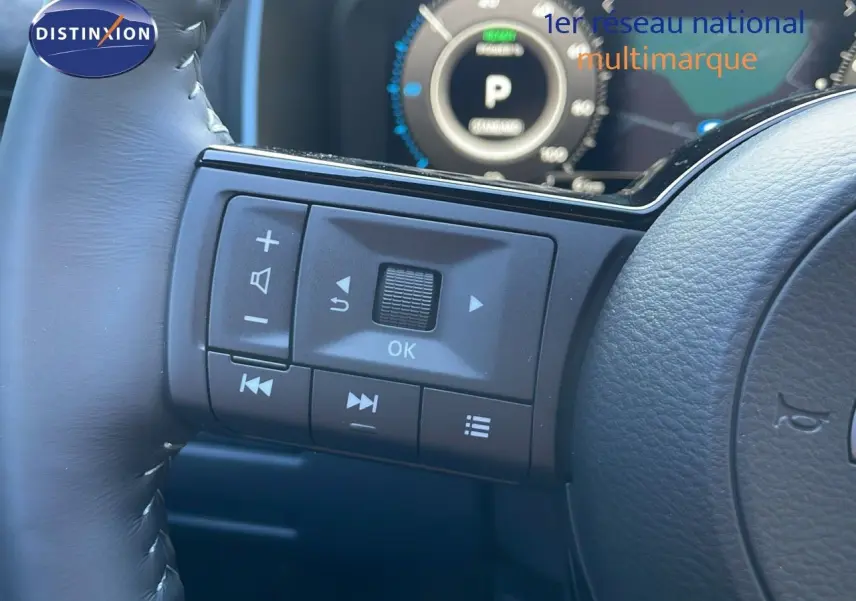 Gros plan sur les commandes au volant du Nissan Qashqai 2025, finition N-Design, avec tableau de bord numérique en arrière-plan.