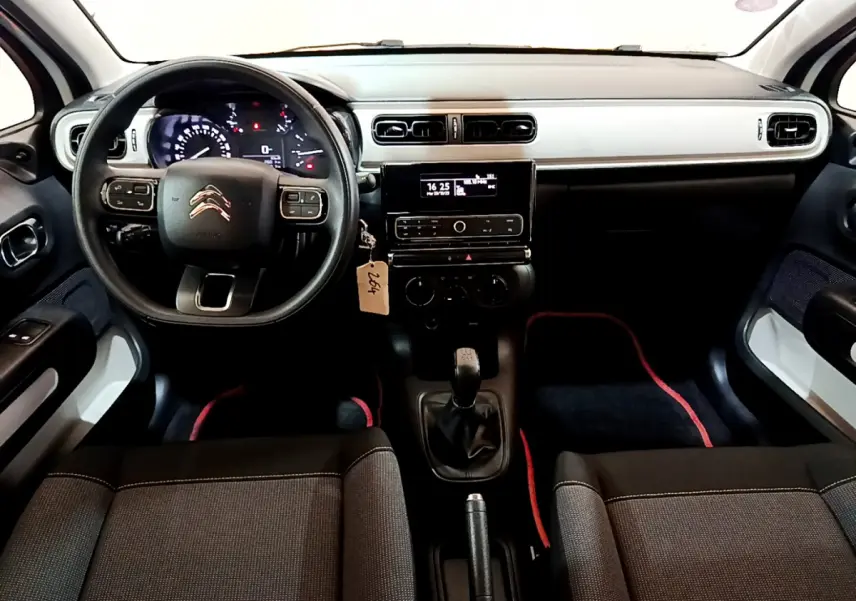 Vue intérieure avant de la Citroën C3 blanche 2018, tableau de bord noir et gris avec volant multifonction et boîte manuelle.