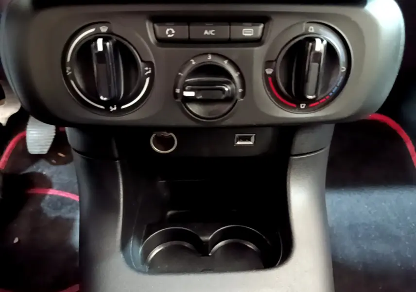 Vue rapprochée de la console centrale noire avec commandes de climatisation et prise USB de la Citroën C3 blanche 2018.