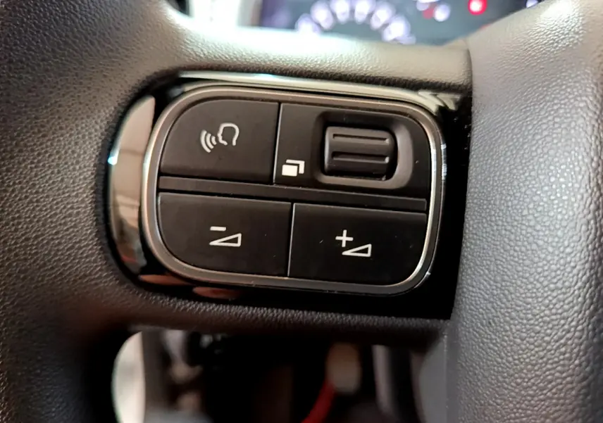 Gros plan sur les commandes noires du volant de la Citroën C3 blanche PureTech 68 BVM Live de 2018.