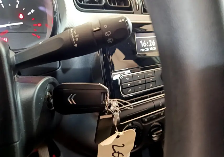 Vue rapprochée de l’intérieur de la Citroën C3 blanche 2018, clé dans le contact et tableau de bord avec horloge digitale.