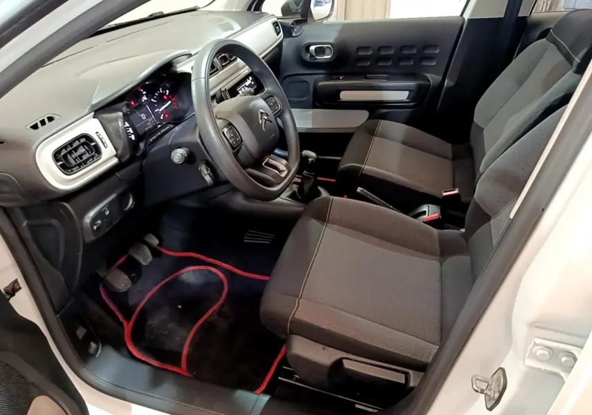 Intérieur avant droit d'une Citroën C3 blanche 2018, montrant le volant, tableau de bord et sièges noirs.