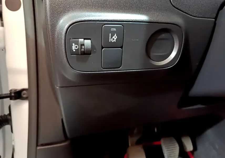 Gros plan sur les commandes de réglage des phares et d'assistance au freinage du côté gauche d'une Citroën C3 blanche 2018.