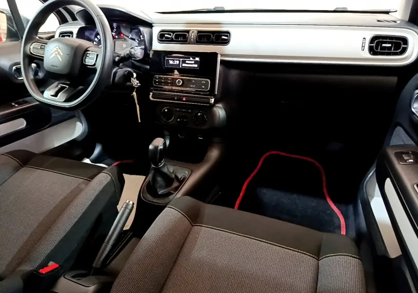 Intérieur avant droit de la Citroën C3 PureTech 68 BVM Live 2018 avec tableau de bord blanc et volant multifonction.