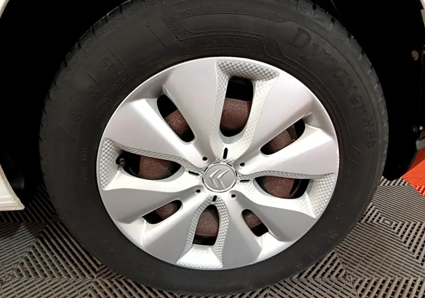 Gros plan sur la roue avant droite d'une Citroën C3 blanche, mettant en valeur la jante en alliage au design moderne.