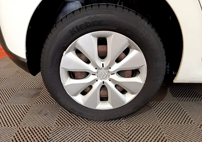 Gros plan sur la roue avant droite d'une Citroën C3 blanche de 2018 avec enjoliveur argenté et logo Citroën central.