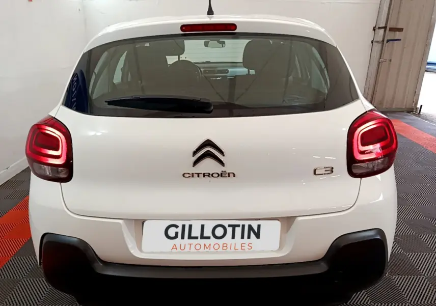 Vue arrière d'une Citroën C3 blanche de 2018 avec feux arrière allumés et logo centré sur le hayon.