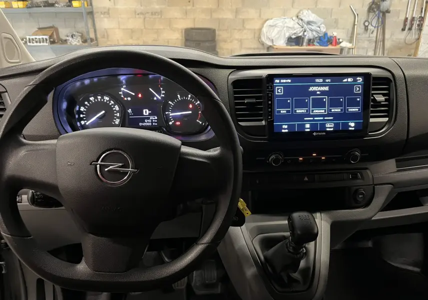 Vue intérieure frontale du tableau de bord gris foncé de l'Opel Vivaro XL 2023 avec volant, écran tactile et levier de vitesses manuel.