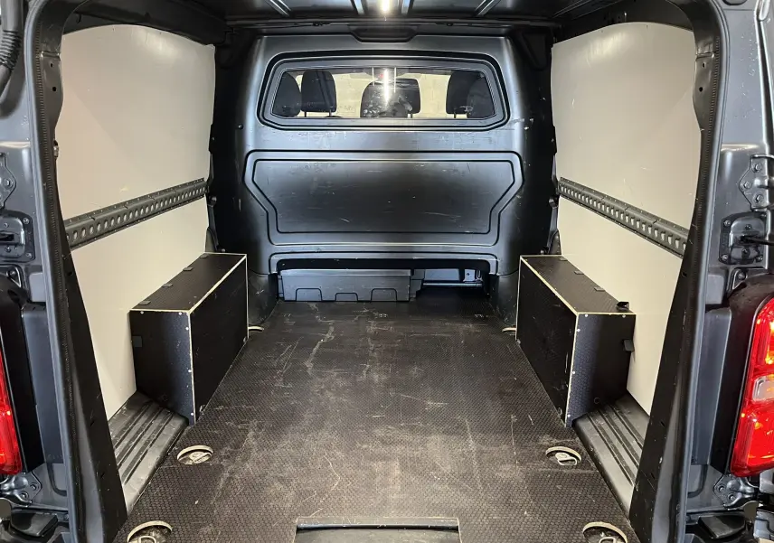 Vue intérieure arrière de l’espace de chargement gris d’un Opel Vivaro XL 2023 avec cloison pleine vitrée et plancher antidérapant.