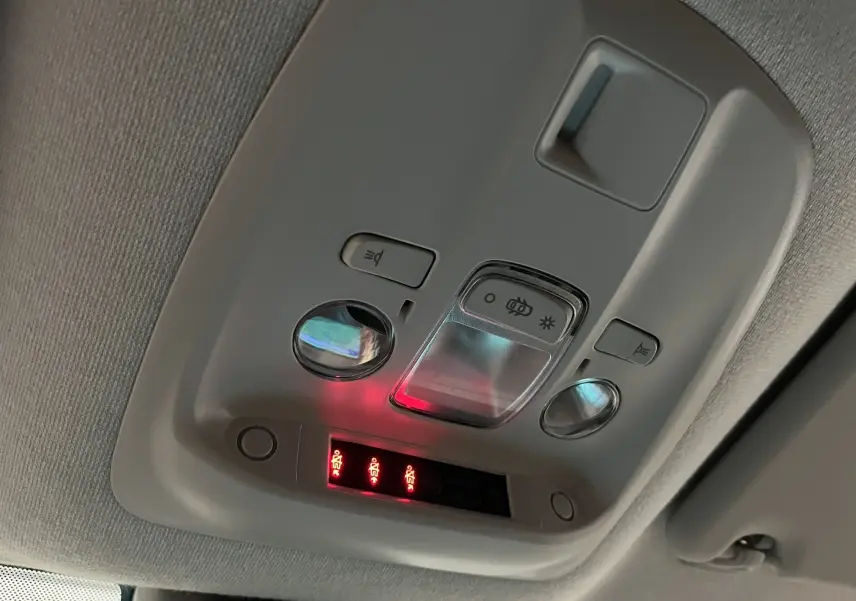 Vue en contre-plongée du plafonnier gris clair de l'Opel Vivaro XL avec commandes d'éclairage et voyants rouges allumés.