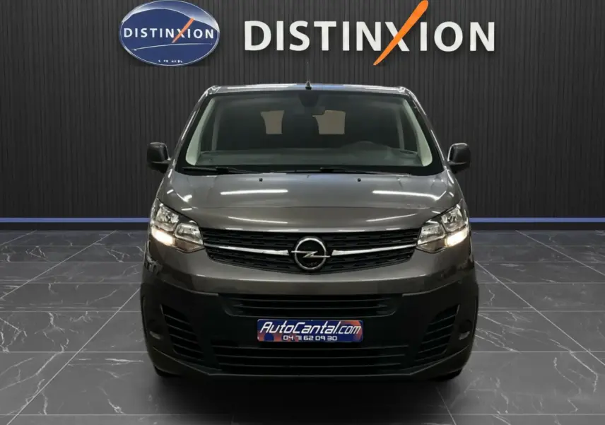 Vue frontale d'un Opel Vivaro Cabine Approfondie gris 2023, avec calandre noire et phares allumés dans un showroom.