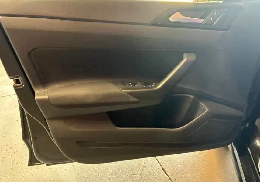 Vue intérieure du panneau de porte côté conducteur de la Volkswagen Polo noire 2022 avec commandes des vitres électriques.