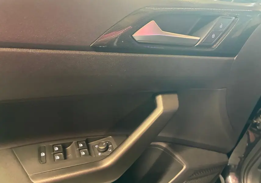 Vue rapprochée de la porte avant gauche noire d'une Volkswagen Polo 2022, avec commandes électriques et poignée intégrée.