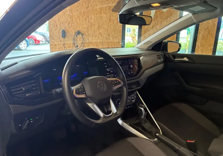 Vue intérieure côté conducteur de la Volkswagen Polo noire 2022, volant multifonctions et tableau de bord moderne.