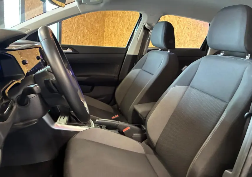 Vue intérieure côté conducteur de la Volkswagen Polo 2022, sièges tissu gris noir et volant multifonctions cuir.
