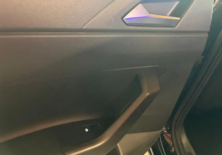 Détail de la poignée intérieure côté droit de la porte arrière d'une Volkswagen Polo noire avec bouton de verrouillage.