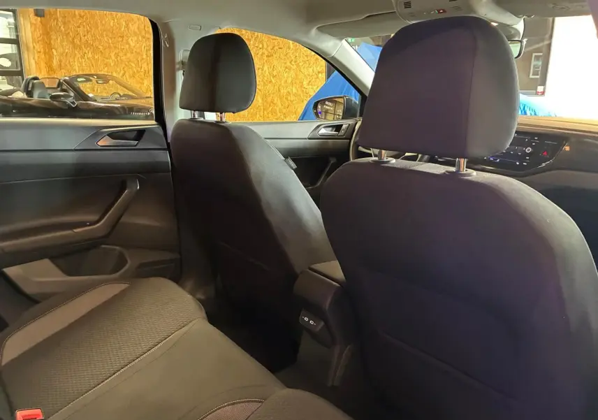 Vue intérieure arrière droite de la Volkswagen Polo noire 2022, sièges tissu gris-noir et console centrale avec ports USB-C.