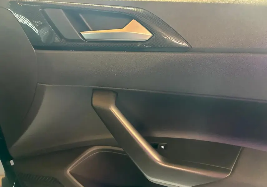 Gros plan sur la poignée de porte côté gauche intérieure d'une Volkswagen Polo noire avec finition tissu gris-noir.