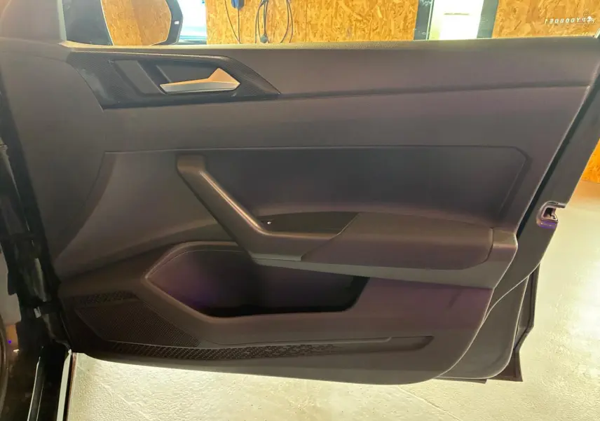 Vue rapprochée de la porte avant gauche noire d’une Volkswagen Polo 2022, avec poignée argentée et panneau noir mat.