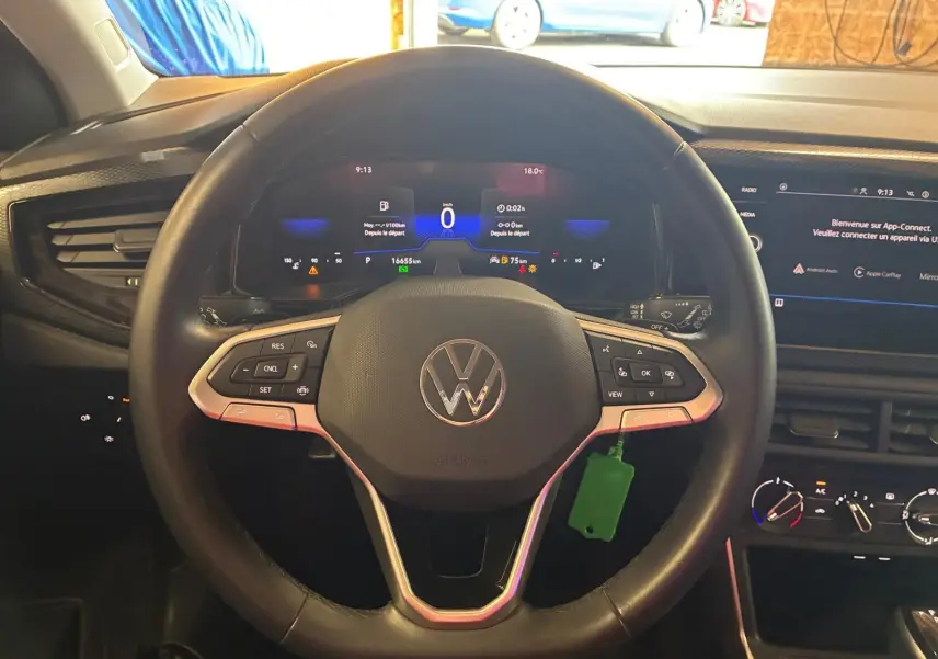Vue intérieure centrée sur le volant noir multifonctions d'une Volkswagen Polo 2022 avec tableau de bord numérique allumé.