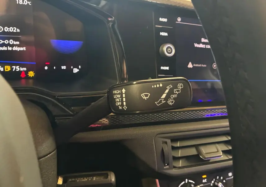 Gros plan sur la commande d’essuie-glace à gauche du volant dans l’habitacle gris noir d’une Volkswagen Polo noire 2022.