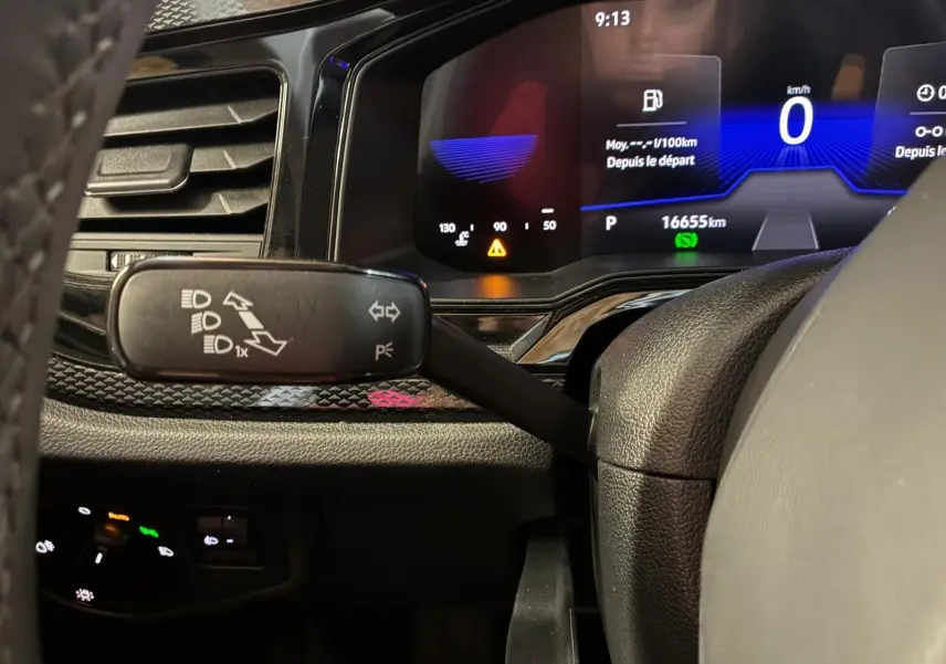 Gros plan sur le combiné d'instruments numérique et la commande de feux au volant d'une Volkswagen Polo noire de 2022.