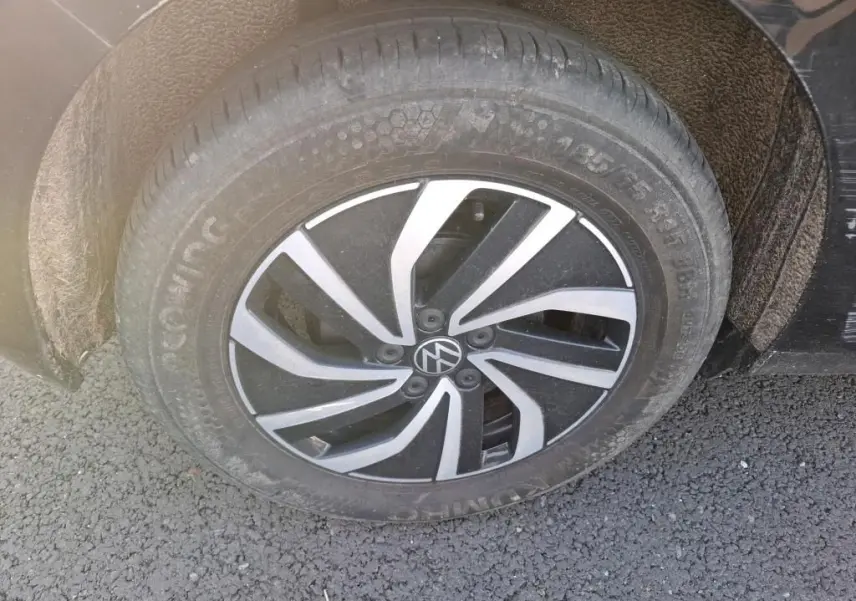 Gros plan sur la roue avant droite noire d'une Volkswagen Polo 1.0 TSI 95 DSG7 Life avec jante alliage bicolore.