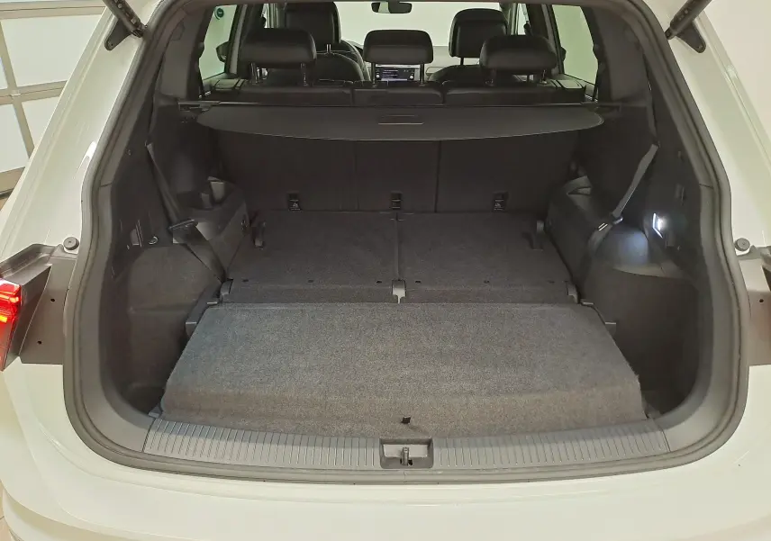 Vue arrière du coffre ouvert du Volkswagen Tiguan Allspace blanc pur 2023, montrant l'espace de chargement avec banquette rabattue.