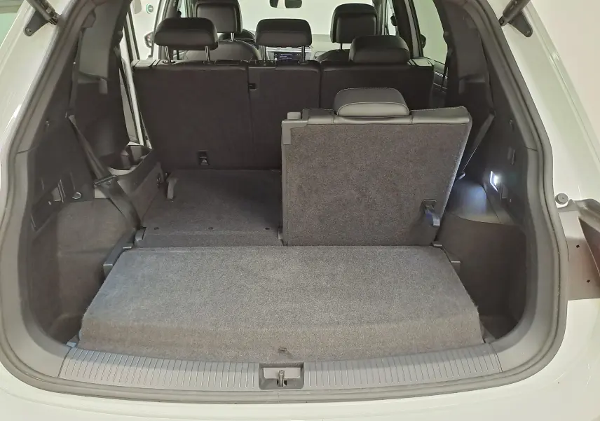 Vue arrière du coffre ouvert du Volkswagen Tiguan Allspace blanc pur 2023, montrant la banquette arrière partiellement rabattue.