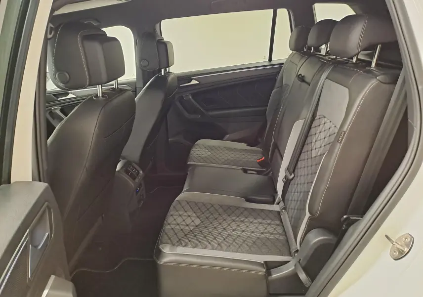 Vue intérieure côté droit des sièges arrière en cuir noir et tissu gris du Volkswagen Tiguan Allspace blanc pur 2023 finition R-Line.