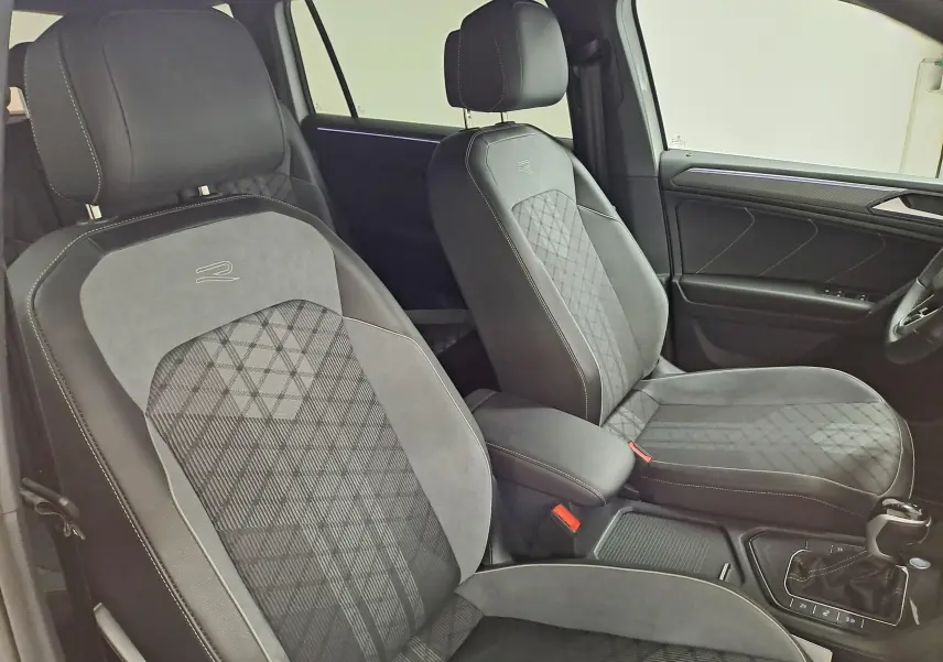 Vue intérieure du Volkswagen Tiguan Allspace 2023 R-Line montrant les sièges avant en tissu noir avec surpiqûres blanches et logo R.