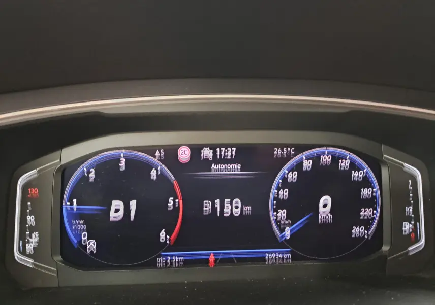 Vue rapprochée du tableau de bord numérique du Volkswagen Tiguan Allspace blanc, affichant la vitesse et l'autonomie.