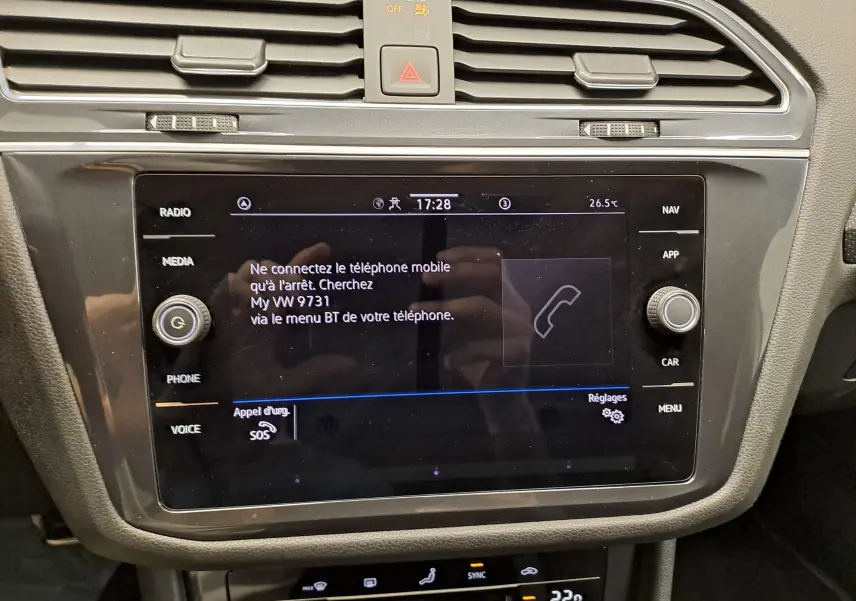 Vue rapprochée de l’écran tactile central noir du Volkswagen Tiguan Allspace blanc, affichant le menu téléphone et commandes multimédia.