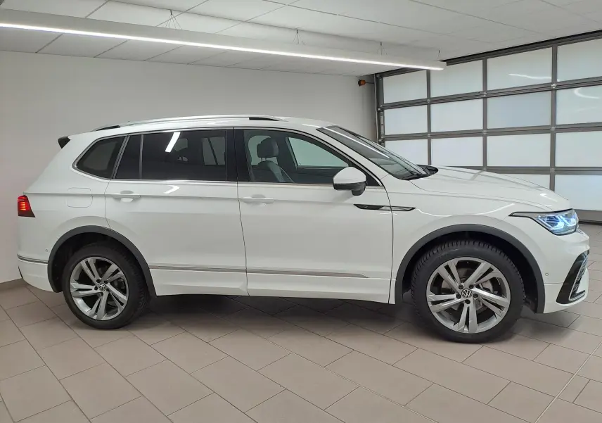 Vue de profil côté gauche du Volkswagen Tiguan Allspace blanc pur 2023 en finition R-Line avec jantes alliage distinctives.