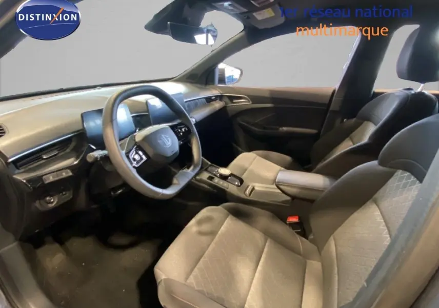 Intérieur de MG3 1.5 Hybrid 2024 vu côté conducteur, sièges tissu gris et tableau de bord moderne noir.