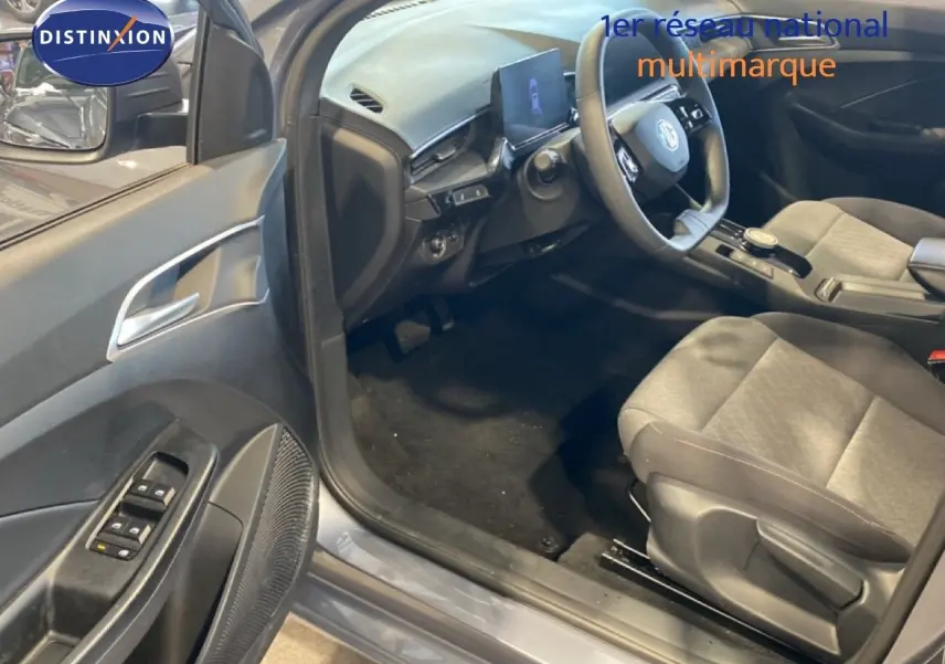 Vue intérieure côté conducteur de la MG3 1.5 Hybrid 2024 en gris Hampstead, montrant sièges tissu gris et tableau de bord moderne.