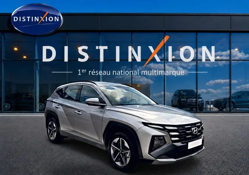 Hyundai Tucson gris shimmering vu en 3/4 avant droit, avec calandre noire et jantes alu 18 pouces.