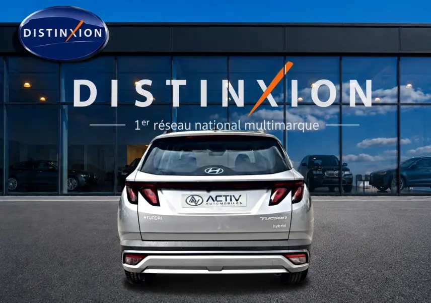 Vue arrière d'un Hyundai Tucson gris shimmering 2026 avec feux LED et logo Activ devant une vitrine Distinxion.
