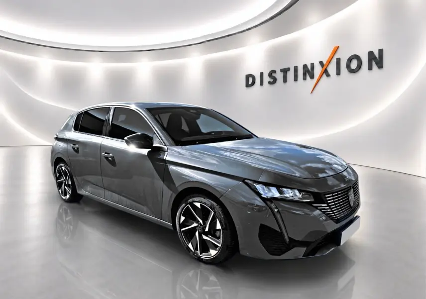 Peugeot 308 gris en 3/4 avant droit dans un showroom lumineux avec jantes alliage et calandre distinctive.