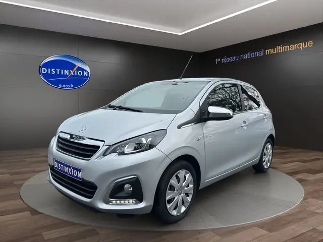 Peugeot 108 gris gallium vue 3/4 avant droit dans un studio, compacte cinq portes avec phares et calandre distinctifs.