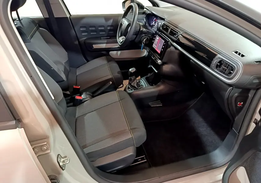 Intérieur avant de la Citroën C3 beige 2022, vue côté conducteur, avec tableau de bord noir et écran tactile central.